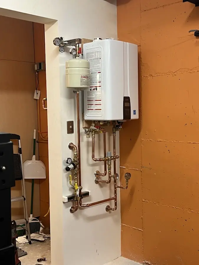 Plumbing technician inspecting water heater connections in McCandless
